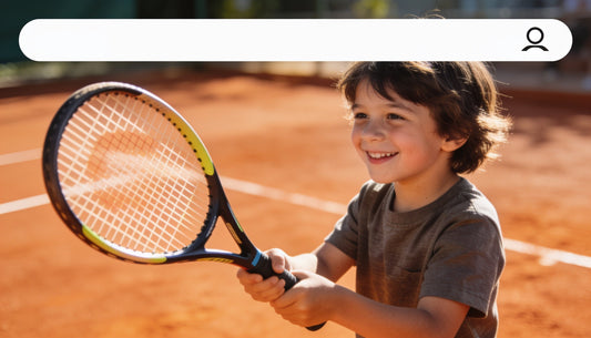 Niño jugando tenis con una raqueta junior en cancha de arcilla