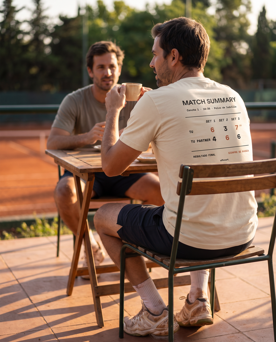 Tenista de espaldas con la polera Match Summary color Beige tomando café en la terraza del club después del partido